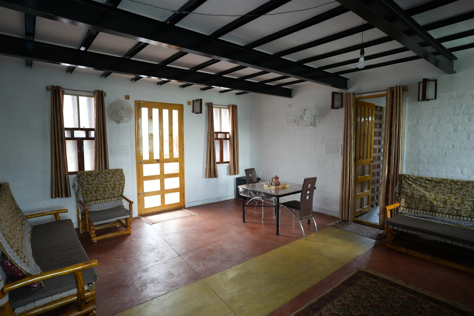 Chateau One living room with seating, a dining table, and yellow entrance doors.